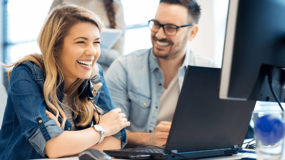 Young woman and man smiling during an online training session.