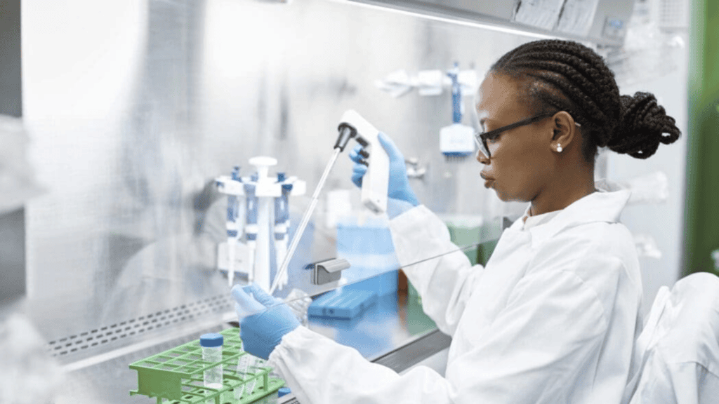 Scientist in a lab coat using a pipette during laboratory research and development work.